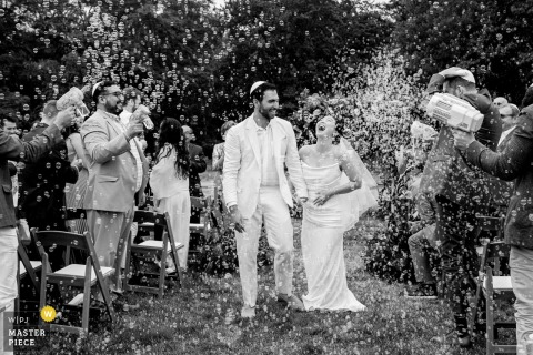 A nostalgic moment captured in Midcoast Maine, as a couple exits their wedding ceremony surrounded by an explosion of bubbles. This black-and-white image, with vintage vibes, is beautifully documented and evokes an old archived photo.