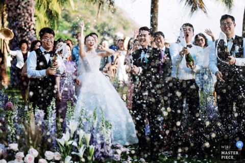 Champagne Celebration at Mandarin Oriental Sanya Lawn Wedding A joyful moment captured at Mandarin Oriental Sanya’s lawn, as the couple celebrates with champagne, their faces expressing pure happiness—beautifully documented in this spirited wedding photo.