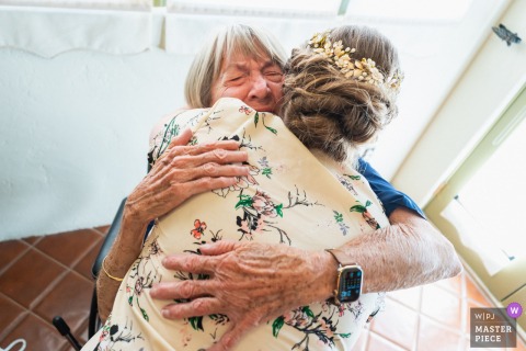 A heartfelt moment captured at Portola Inn, California, as the bride’s grandmother, emotion on her face, gives a loving and emotional hug to the bride, beautifully documented in this wedding photo.