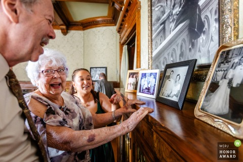 Inside Joslyn Castle in Omaha, NE, the grandmother of the groom gazes at her own wedding photo, laughing warmly as she reminisces about her younger days.