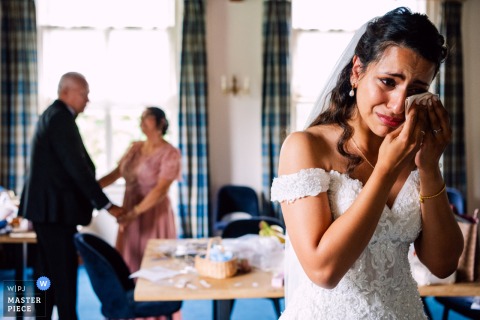  At Kasteel van Rhoon in the Netherlands, the bride is overcome with emotion when her divorced parents greet each other during the ceremony, creating a powerful, heartfelt family moment.
