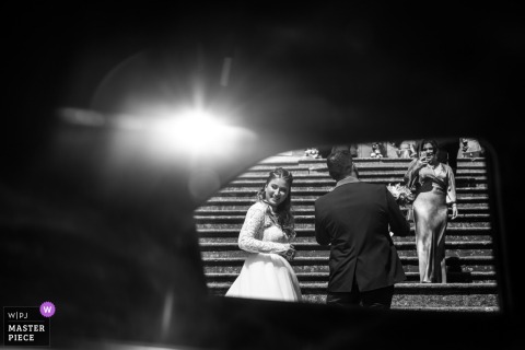 Glimpses Of The Bride Seen Through A Vintage Car Window Outside Chiesa Del Crocifisso, Longiano, Before Entering For Her Ceremony. Through the window of a vintage car outside Chiesa del Crocifisso in Longiano, Italy, one can glimpse the bride, moments before she enters the church to begin her ceremony.