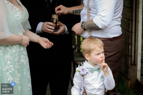 A Confident Pageboy Silences Guests With A Gesture During The Ceremony At The Wedding Venue In Victoria, Australia. The pageboy steals the scene at the ceremony location in Victoria, Australia, confidently signaling everyone to be silent.