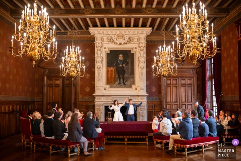 Triumphant Arms Are Raised By Newlyweds At The La Rochelle Town Hall, Celebrating Their Union Before Smiling Guests. At the town hall in La Rochelle, France, the newlyweds triumphantly raise their arms before their guests, celebrating together after exchanging wedding rings.