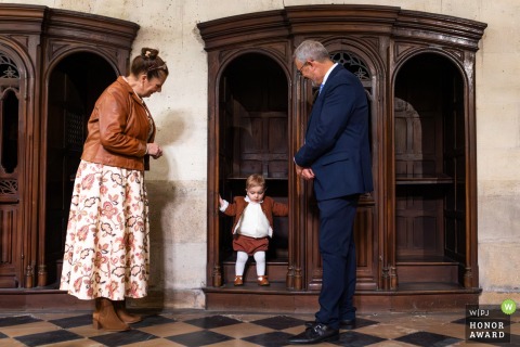 Inside Basilique Notre-Dame de Verdelais in Gironde, France, grandparents lovingly watch over their grandson during a tender family moment in the church.
