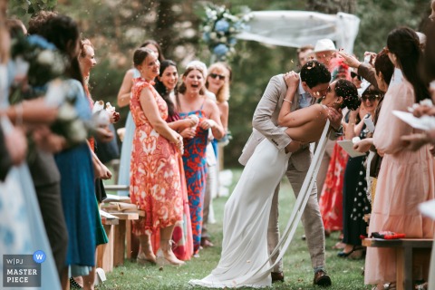   Domaine des Gaillardoux in Lot, France, sees the couple conclude their ceremony with a dip and kiss, surrounded by friends and family, with smiles reflecting the joy of the occasion.
