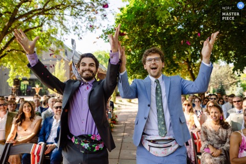   Flower guys bring playful energy to the start of the ceremony at River Bend in Lyons, Colorado, as they toss petals and entertain guests before the couple’s entrance.