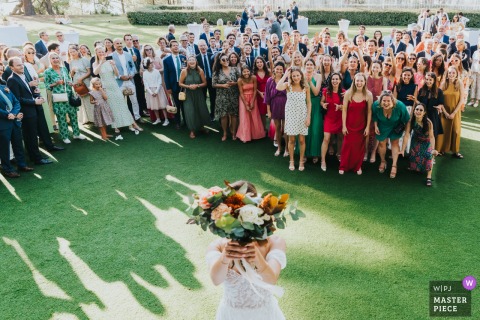   Excitement builds at Salle du Tir au vol in Arcachon as the bride tosses her bouquet, with eager guests vying for a chance to catch the symbolic flowers.