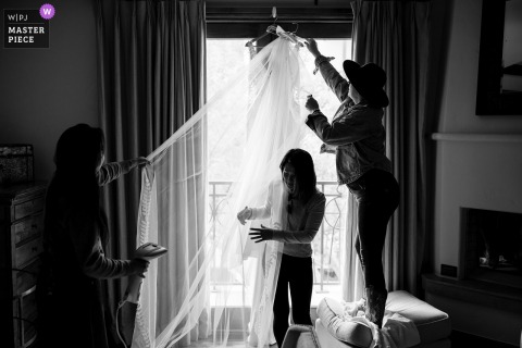 Before The Wedding Begins, Friends Carefully Arrange The Bride’s Veil At The Arrabelle With Mountains As The Backdrop. The Arrabelle serves as the backdrop while friends carefully tend to the bride’s veil, making final adjustments and ensuring she’s perfect before the wedding begins.