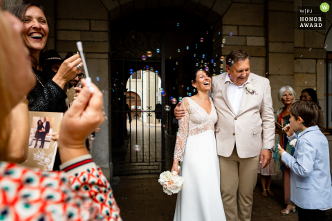 At City Hall in Vienne, Isère, the newlyweds walk out to a cheerful shower of bubbles, lovingly blown by their guests as they exit the venue together.