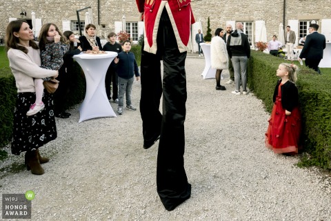 A stilt-walker gracefully mingles with guests during cocktail hour at Domaine de la Chartrognière in Drôme, adding whimsical charm to this lively wedding party.