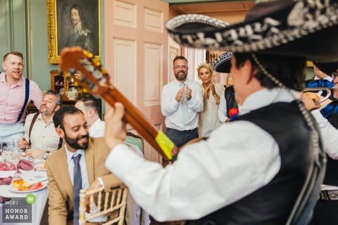 At Stanford Hall in Lutterworth, the couple enjoys the lively sounds of a mariachi band, watching the performance with their guests in the elegant venue.