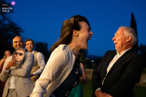   Tenuta Lupinari in Arezzo, Italy, hosts wild fun as a bridesmaid screams in the groom’s father’s face during a hilarious wedding game, laughter echoing through the Tuscan venue.