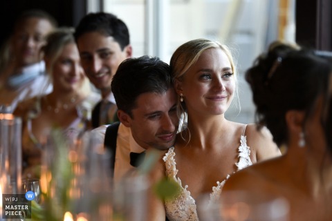   A couple shares a cozy embrace at Saltwater Farm Vineyard in Stonington, CT, listening to the bride’s sister deliver a touching toast during the reception.