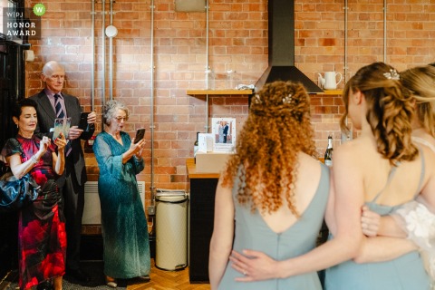 At The Pumping House in Nottinghamshire, three guests with cameras photograph bridesmaids in the foreground, perfectly capturing candid moments of the celebration at the venue.