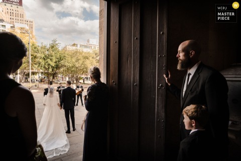 San Antonio’s San Fernando Cathedral Bursts To Life As The Couple Exits To Brilliant Light And Festive Mariachi Sounds. Inside the shadowed doorway of San Fernando Cathedral in San Antonio, the couple bursts out into brilliant light, vibrant sound, and a festive welcome from the city and mariachis.