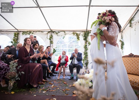 The Couple Steal A Private, Playful Kiss Just Before Their Brittany Celebration Begins, Savouring An Intimate Moment Together. The couple playfully hides their kiss upon meeting at the ceremony location in Brittany, savoring a private moment just before the official celebration begins.