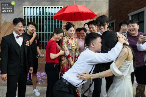 During festivities at home in China, the bride and groom watch their groomsmen and bridesmaids partake in the lively bride-carrying game, adding joy and fun for the whole family.