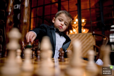 Ring Bearer Finds Calm Playing Chess Before Ceremony At The Whiteface Lodge Wedding Venue In Upstate New York The ring bearer at The Whiteface Lodge takes a quiet moment to play chess before the ceremony, enjoying some calm at the ceremony and reception location.