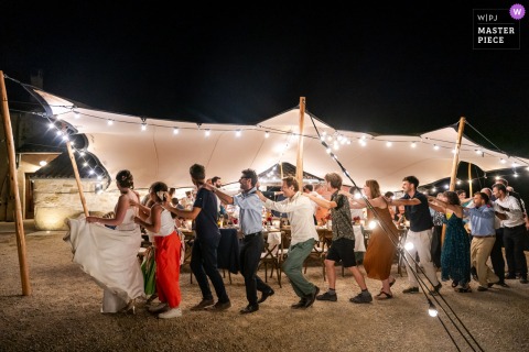 Guests Perform The Duck Dance In Die, France, Filling The Tent Venue With Laughter During A Beloved Tradition. Guests enthusiastically participate in the duck dance at a wedding in Die, France, with laughter filling the tent venue as everyone joins this lighthearted dance tradition.