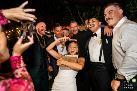 At Tivoli Italian Villa in Fallbrook, California, a guest gathers friends for a group cigar photo, each holding the cigars gifted by the groom at this lively wedding venue.