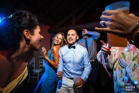   Guests at Mas de Montet in Dordogne dance closely, laughing and singing with drinks in hand as the energy peaks during this lively wedding reception in the French countryside.