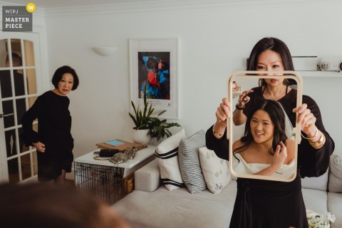   While getting ready in London, the bride’s sister holds up a mirror, offering encouragement and ensuring everything is perfect.