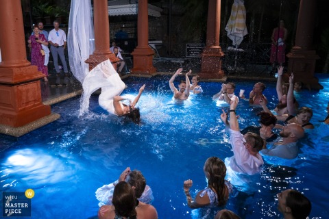   To end a memorable night at Zephyr Palace, Villa Caletas Hotel in Jaco, Costa Rica, the bride surprises everyone by jumping backwards into the stunning infinity pool.