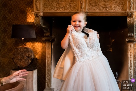   At Kasteel Wijenburg, a young bridesmaid bravely holds up the bride’s dress but hesitates with uncertainty, adding a charming touch of innocence to this traditional wedding role.