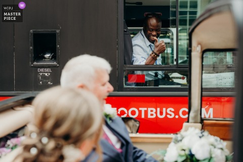 Cheerful Bus Driver Gives The Bride A Warm Welcome Upon Her Arrival For A Bath Wedding Ceremony. The bus driver offers a cheerful thumbs up to the bride as she arrives in Bath for her wedding ceremony, adding a friendly, welcoming touch to the start of her day.
