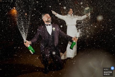 Champagne Bottles Burst With Bubbles As The Couple Arrives At Their Cocktail Reception At Arènes De Doué, Doué La Fontaine, France. Aud Champagne bottles erupt with sparkling bubbles as the bride and groom arrive at their cocktail reception at Arènes de Doué in Doué la Fontaine, France.