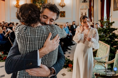   Emotion runs high during the secular ceremony at Château de Denonville in France, with the groom hugging his sister while the bride gently wipes away tears in the background.