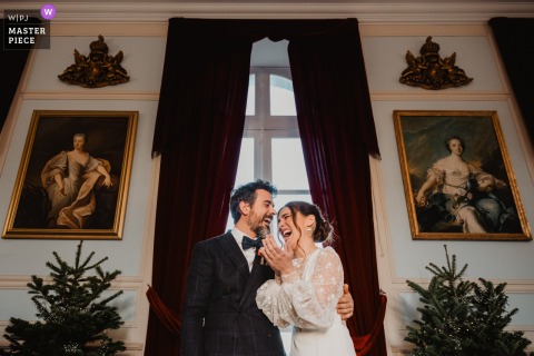 Joyful Laughter Erupts During The Secular Ceremony At Château De Denonville, France, As The Couple Smile Before Guests. Laughter fills the air during the secular ceremony at Château de Denonville, France, as the bride and groom share a joyful moment together in front of their guests.