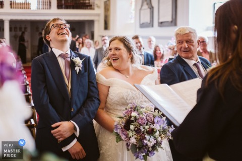   Shared laughter during wedding vows brings the bride and groom closer at Hazlewood Castle in West Yorkshire, UK, making the moment even more memorable for them and their guests.
