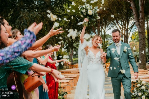 Flower Petals Cascade Over The Couple Exiting Domaine Du Petit Malherbes, Marking A Joyful Secular Ceremony In France. Flower petals rain down on the couple as they exit the secular ceremony at Domaine du petit Malherbes.