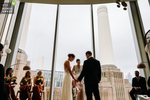 While exchanging vows in front of Battersea Power Station, the bride and groom look warmly at their son, including him in this important ceremony.
