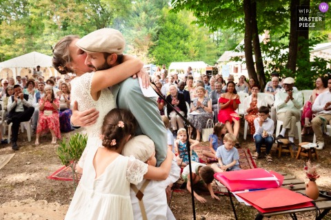 After Outdoor Ceremonies At La Bois Des Anglais, France, The Couple Share A Loving Hug As Their Day Ends. After the outdoor ceremony celebration at La Bois des Anglais, France, the bride and groom share a meaningful final hug, surrounded by loved ones as their wedding day draws to a close.
