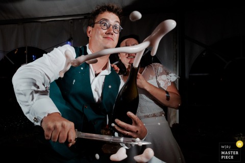 Champagne Is Popped By The Couple Amid Laughter, Highlighting Celebration’s High Point In Kerlouan, France. In Kerlouan, a champagne bottle is opened by the couple, celebrating and laughter as the bubbly marks a highlight of the festivities.