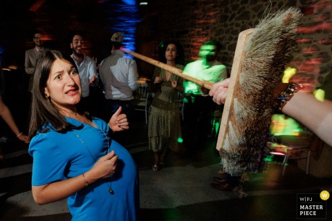 An Expectant Guest Attempts The Limbo As Cheers Erupt During A Festive Reception Contest In Paris, France. During a limbo contest in Paris, an expectant guest attempts to duck under the bar, her expression revealing both excitement and concern as everyone cheers her on.