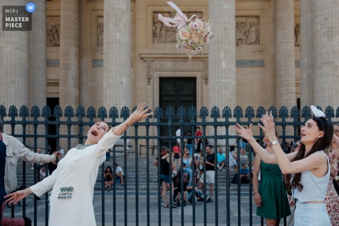 Only One Woman Waits Poised For The Toss As The Bouquet Flies Following Town Hall Ceremony In Paris. Just after the town hall ceremony in Paris, only one woman stands poised to catch the bouquet as it sails through the air during the traditional bouquet toss.