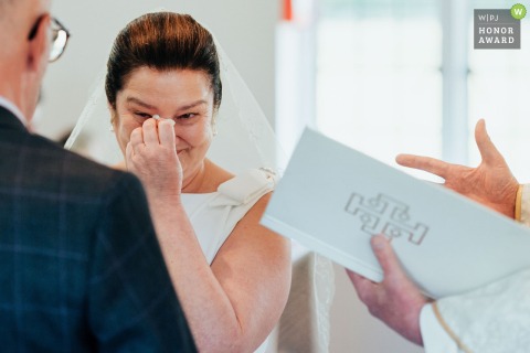 During vows at That Amazing Place in Harlow, Essex, the bride delicately wipes away a tear, moved by the emotional exchange with her husband.