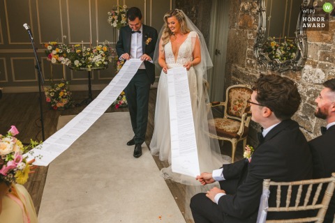 At Boyne Hill House wedding ceremony, the bride and groom unravel printed answers in response to the celebrant's questions, sharing laughter and surprise with their guests.