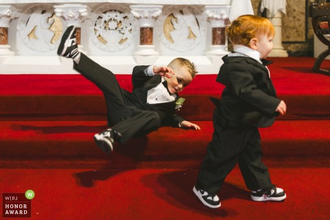 A page boy takes a tumble at the altar during the ceremony at Roundwood Church, bringing a touch of playful spontaneity to this heartfelt occasion.