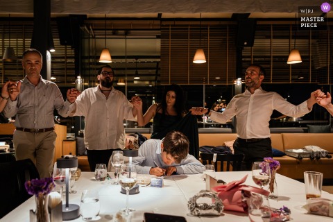 As Guests Dance At Litera Restaurant In Istanbul, The Couple’s Nephew Writes His Loving Wishes For The Newlyweds. At Litera Restaurant in Istanbul, as guests dance in celebration, the couple’s young nephew quietly writes his heartfelt wishes to the bride and groom at a table nearby.