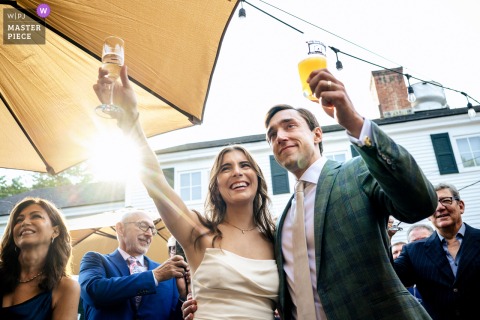   At Grafton Inn in Grafton, Vermont, the bride and groom raise glasses as they give a cheerful toast during their wedding reception, smiles reflecting their happiness.