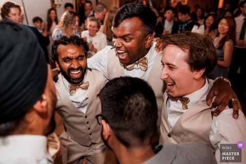 Joyful Groomsmen Dominate The Dance Floor During Festive Nighttime Celebration At Chenies Manor In Buckinghamshire, United Kingdom. The groomsmen celebrate enthusiastically on the dance floor at Chenies Manor in Buckinghamshire, United Kingdom, filling the historic venue with energy during the evening festivities.