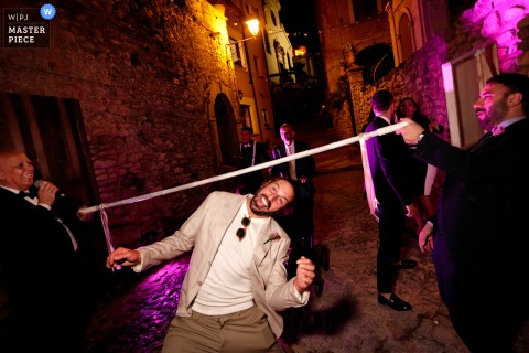   Guests at Restaurant Zio Salvatore in Siderno Superiore, Calabria participate in a fun entry challenge before joining the wedding celebration, setting a lively and engaging tone for the festivities.