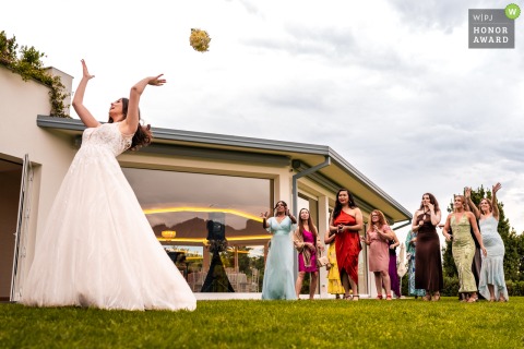In the gardens of Villa Dolceacqua, Oggiono, Lake Como, Italy, the bride tosses her bouquet to a crowd of eager guests during this classic wedding tradition.