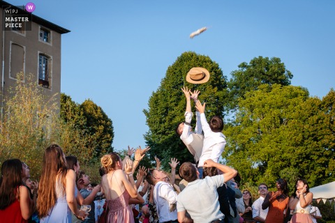 Laughter And Competition Fill Espace Montgontier In Gillonnay, France, As Guests Participate In Lively Sausage Tosses During Reception. At Espace Montgontier in Gillonnay, France, wedding guests take part in lively sausage throws during the reception, filling the venue with laughter and spirited competition.