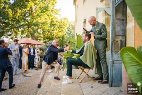 At Chateau Lacoste in Lupiac, Gers, guests watch in amusement as the groom shaves his brother’s hair, creating a playful, unexpected scene during the celebration.